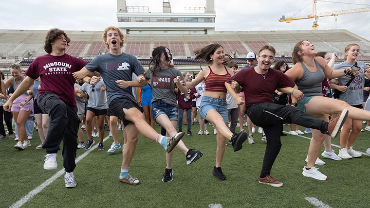 Six Missouri State students energetically perform a kickline dance at Plaster Stadium.